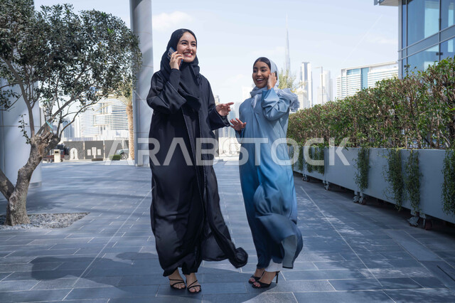 قضاء أوقات ممتعة مع الاصدقاء ، التواصل مع العائلة عبر الجوال ، اجراء المكالمات الهاتفية ، سيدتان اماراتيان تقومان بالتنزه في وقت العطلة ، الإستمتاع مع الأصدقاء, التجول في إحدى المناطق العامة ، صديقتان عربيتان خليجيتان سعوديتان مبتسمتان تسيران معاً في نزهة ممتعة لإحدى الأماكن الترفيهية ، علاقات اجتماعية .