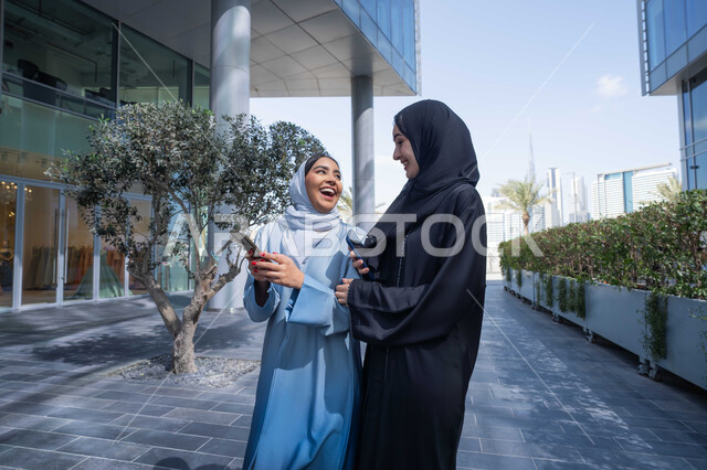 التجول في إحدى المناطق العامة ، قضاء وقت الفراغ بالدردشة مع الصديقات ، صديقتان عربيتان خليجيتان سعوديتان مبتسمتان تسيران معاً في نزهة ممتعة لإحدى الأماكن الترفيهية ، سيدتان اماراتيان تقومان بالتنزه في وقت العطلة ، صداقات و تعارف ، علاقات اجتماعية ، قضاء أوقات ممتعة .