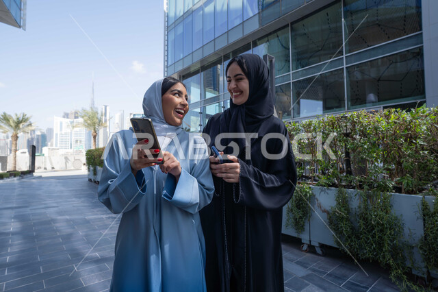قضاء وقت الفراغ بالدردشة مع الصديقات ، صديقتان عربيتان خليجيتان سعوديتان مبتسمتان تسيران معاً في نزهة ممتعة لإحدى الأماكن الترفيهية ، امراتان اماراتيان تقومان بالتنزه في وقت العطلة ، صداقات و تعارف ، علاقات اجتماعية ، قضاء أوقات ممتعة .