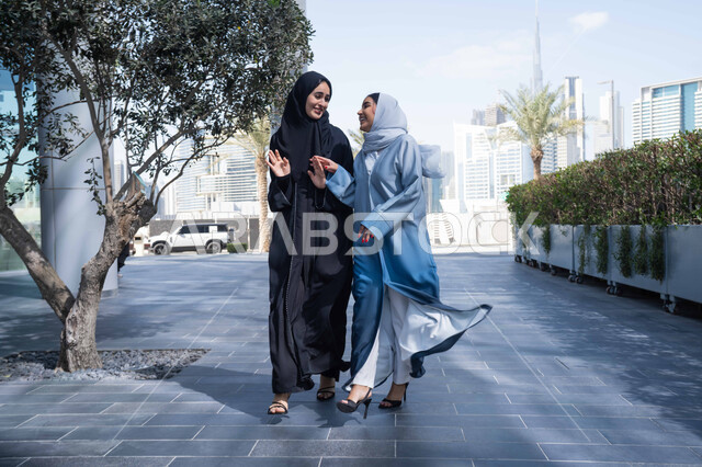 تعابير التحديد والتأكيد، اشارات تحدد هذا المكان (هنا) ، تقوية وتعزيز العلاقات الاجتماعية ، صديقتان عربيتان خليجيتان سعوديتان محجبتان ترتديان العباءات والحجاب، قضاء أوقات ممتعة في الطبيعة ، مفهوم الأناقة والاهتمام بالمظهر الخارجي ، استنشاق الهواء النقي في وقت النهار .