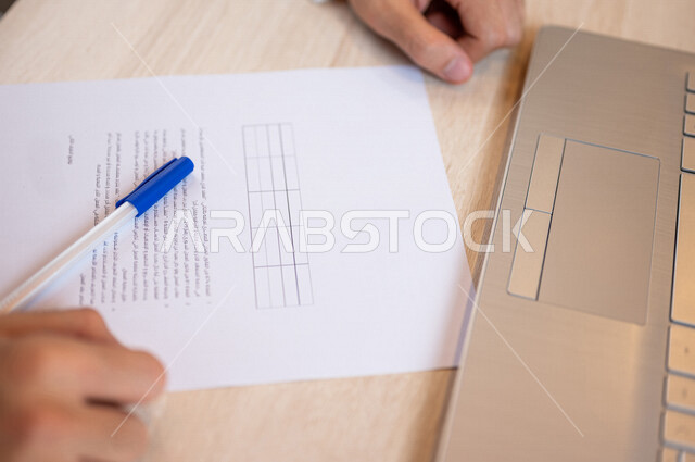 رجل عربي خليجي سعودي يجلس أمام الحاسوب المحمول ويقوم بتجهيز جدول الأعمال، سكرتير يدير الاعمال الورقية، تنظيم جدول الاعمال والمهام، أعمال مكتبية