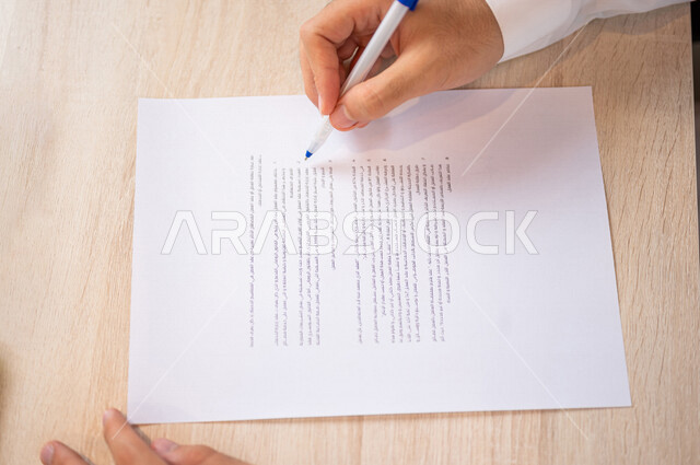 A Saudi Arabian Gulf man holding a financial offer paper in his hand, reading the terms of the offer, checking and checking the financial offer, approving the financial offer