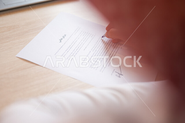 رجل عربي خليجي سعودي يمسك بيده ورقة عرض مالي، قراءة بنود العرض، التحقق والتدقيق في العرض المالي، الموافقة على العرض المالي