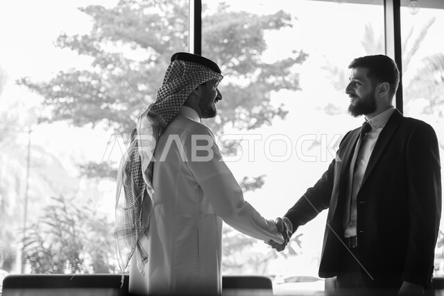 اجراء مقابلة توظيف واختبار، تبادل المعلومات والخبرات، رجل اعمال عربي سعودي خليجي يرتدي الثوب التقليدي والشماغ يصافح شاب يرتدي البدلة الرسمية، اتفاقية عمل لمشروع جديد، الموافقة على شروط العمل، توقيع عقود العمل