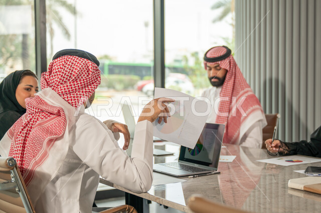 شرح و تحليل الرسوم البيانية, دمج الأجهزة التقنية الحديثة بالأعمال المكتبية، دراسة أوراق البيانات الإحصائية, تطوير المشاريع و الاستثمارات, إدارة و تقسيم المهام، فريق عمل عربي خليجي سعودي يقوم بإجراء اجتماع عمل داخل غرفة الاجتماعات في مقر الشركة