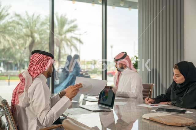شرح و تحليل الرسوم البيانية, دمج الأجهزة التقنية الحديثة بالأعمال المكتبية، دراسة أوراق البيانات الإحصائية, تطوير المشاريع و الاستثمارات, إدارة و تقسيم المهام، فريق عمل عربي خليجي سعودي يقوم بإجراء اجتماع عمل داخل غرفة الاجتماعات في مقر الشركة