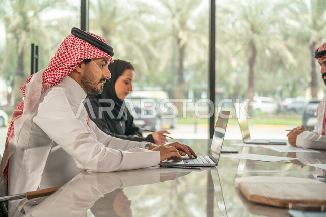 شرح و تحليل الرسوم البيانية, دمج الأجهزة التقنية الحديثة بالأعمال المكتبية، دراسة أوراق البيانات الإحصائية, تطوير المشاريع و الاستثمارات, إدارة و تقسيم المهام، فريق عمل عربي خليجي سعودي يقوم بإجراء اجتماع عمل داخل غرفة الاجتماعات في مقر الشركة