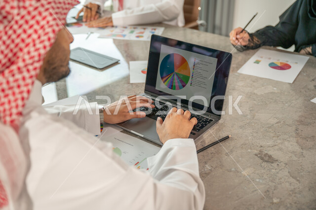 شرح و تحليل الرسوم البيانية, دمج الأجهزة التقنية الحديثة بالأعمال المكتبية، دراسة أوراق البيانات الإحصائية, تطوير المشاريع و الاستثمارات, إدارة و تقسيم المهام، فريق عمل عربي خليجي سعودي يقوم بإجراء اجتماع عمل داخل غرفة الاجتماعات في مقر الشركة