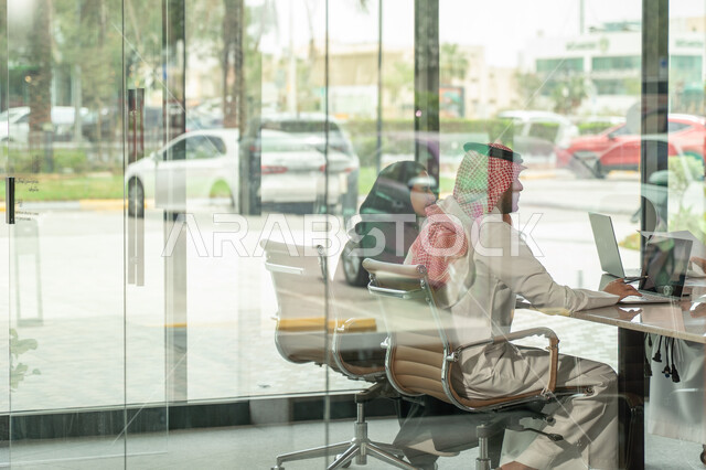 Explaining and analyzing graphs, integrating modern technical devices into office work, studying statistical data sheets, developing projects and investments, managing and dividing tasks, an Arab Gulf Saudi team conducting a business meeting in the conference room at the company's headquarters