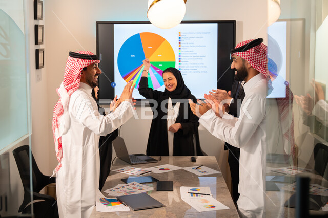 دمج الأجهزة التقنية الحديثة بالأعمال المكتبية، دراسة أوراق البيانات الإحصائية, تطوير المشاريع و الاستثمارات, إدارة و تقسيم المهام، فريق عمل عربي خليجي سعودي يقوم بإجراء اجتماع عمل داخل غرفة الاجتماعات في مقر الشركة، شرح و تحليل الرسوم البيانية