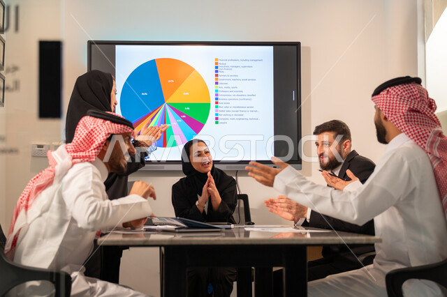 دمج الأجهزة التقنية الحديثة بالأعمال المكتبية، دراسة أوراق البيانات الإحصائية, تطوير المشاريع و الاستثمارات, إدارة و تقسيم المهام، فريق عمل عربي خليجي سعودي يقوم بإجراء اجتماع عمل داخل غرفة الاجتماعات في مقر الشركة، شرح و تحليل الرسوم البيانية