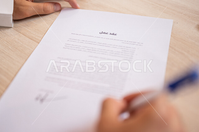 رجل عربي خليجي سعودي يقوم بالتوقيع على عقد عمل، قراءة البنود الخاصة بالعقد، التحقق والتدقيق في شروط العقد، سكرتير يدير الاعمال الورقية، الموافقة على الشروط