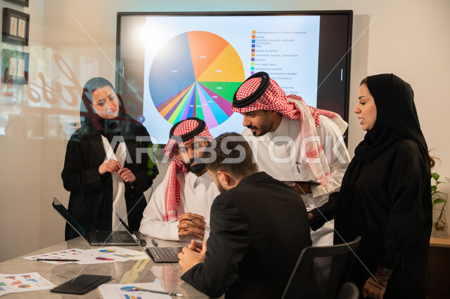 دمج الأجهزة التقنية الحديثة بالأعمال المكتبية، دراسة أوراق البيانات الإحصائية, تطوير المشاريع و الاستثمارات, إدارة و تقسيم المهام، فريق عمل عربي خليجي سعودي يقوم بإجراء اجتماع عمل داخل غرفة الاجتماعات في مقر الشركة، شرح و تحليل الرسوم البيانية