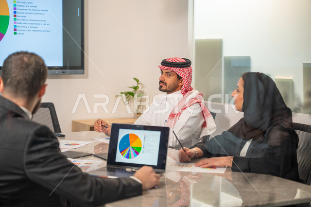  إدارة و تقسيم المهام، فريق عمل عربي خليجي سعودي يقوم بإجراء اجتماع عمل داخل غرفة الاجتماعات في مقر الشركة، شرح و تحليل الرسوم البيانية, دمج الأجهزة التقنية الحديثة بالأعمال المكتبية، دراسة أوراق البيانات الإحصائية, تطوير المشاريع و الاستثمارات
