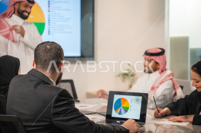  إدارة و تقسيم المهام، فريق عمل عربي خليجي سعودي يقوم بإجراء اجتماع عمل داخل غرفة الاجتماعات في مقر الشركة، شرح و تحليل الرسوم البيانية, دمج الأجهزة التقنية الحديثة بالأعمال المكتبية، دراسة أوراق البيانات الإحصائية, تطوير المشاريع و الاستثمارات