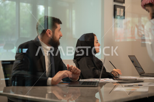  إدارة و تقسيم المهام، فريق عمل عربي خليجي سعودي يقوم بإجراء اجتماع عمل داخل غرفة الاجتماعات في مقر الشركة، شرح و تحليل الرسوم البيانية, دمج الأجهزة التقنية الحديثة بالأعمال المكتبية، دراسة أوراق البيانات الإحصائية, تطوير المشاريع و الاستثمارات