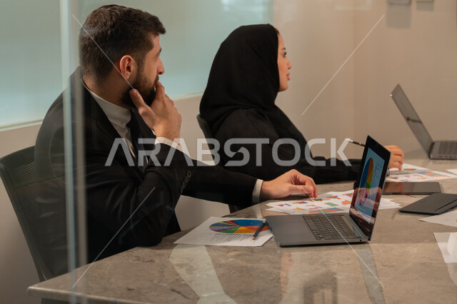  إدارة و تقسيم المهام، فريق عمل عربي خليجي سعودي يقوم بإجراء اجتماع عمل داخل غرفة الاجتماعات في مقر الشركة، شرح و تحليل الرسوم البيانية, دمج الأجهزة التقنية الحديثة بالأعمال المكتبية، دراسة أوراق البيانات الإحصائية, تطوير المشاريع و الاستثمارات