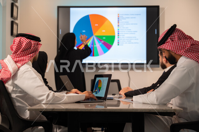  إدارة و تقسيم المهام، فريق عمل عربي خليجي سعودي يقوم بإجراء اجتماع عمل داخل غرفة الاجتماعات في مقر الشركة، شرح و تحليل الرسوم البيانية, دمج الأجهزة التقنية الحديثة بالأعمال المكتبية، دراسة أوراق البيانات الإحصائية, تطوير المشاريع و الاستثمارات