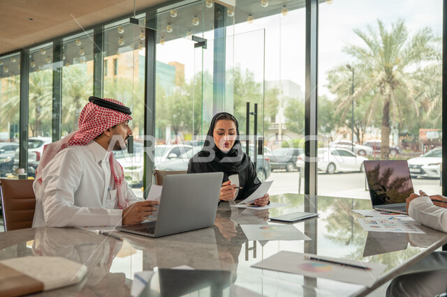  تبادل الخبرات والمعلومات لتحقيق الاهداف, موظفان عربيان خليجيان سعوديان يجلسان على مكتبهم داخل مقر الشركة، استخدام الحاسب والتقنية في مجال الاعمال، بيئة العمل المريحة في الشركات السعودية، الحوار و النقاش بين الزملاء