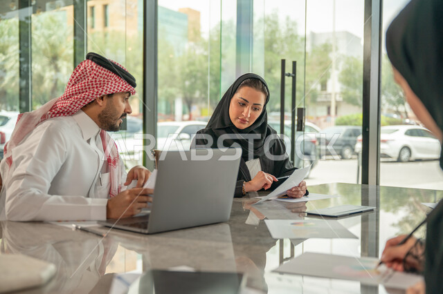  تبادل الخبرات والمعلومات لتحقيق الاهداف, موظفان عربيان خليجيان سعوديان يجلسان على مكتبهم داخل مقر الشركة، استخدام الحاسب والتقنية في مجال الاعمال، بيئة العمل المريحة في الشركات السعودية، الحوار و النقاش بين الزملاء