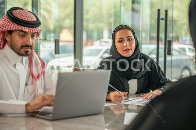  تبادل الخبرات والمعلومات لتحقيق الاهداف, موظفان عربيان خليجيان سعوديان يجلسان على مكتبهم داخل مقر الشركة، استخدام الحاسب والتقنية في مجال الاعمال، بيئة العمل المريحة في الشركات السعودية، الحوار و النقاش بين الزملاء