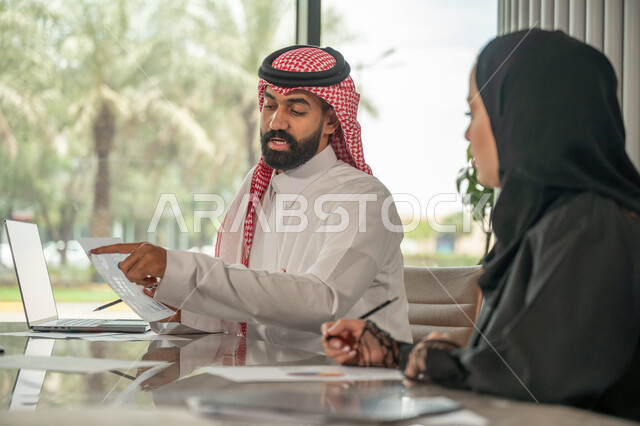  تبادل الخبرات والمعلومات لتحقيق الاهداف, موظفان عربيان خليجيان سعوديان يجلسان على مكتبهم داخل مقر الشركة، استخدام الحاسب والتقنية في مجال الاعمال، بيئة العمل المريحة في الشركات السعودية، الحوار و النقاش بين الزملاء