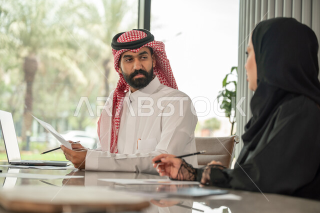  تبادل الخبرات والمعلومات لتحقيق الاهداف, موظفان عربيان خليجيان سعوديان يجلسان على مكتبهم داخل مقر الشركة، استخدام الحاسب والتقنية في مجال الاعمال، بيئة العمل المريحة في الشركات السعودية، الحوار و النقاش بين الزملاء