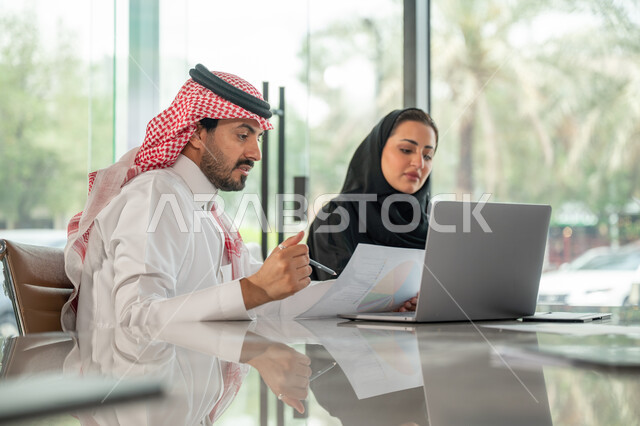  تبادل الخبرات والمعلومات لتحقيق الاهداف, موظفان عربيان خليجيان سعوديان يجلسان على مكتبهم داخل مقر الشركة، استخدام الحاسب والتقنية في مجال الاعمال، بيئة العمل المريحة في الشركات السعودية، الحوار و النقاش بين الزملاء