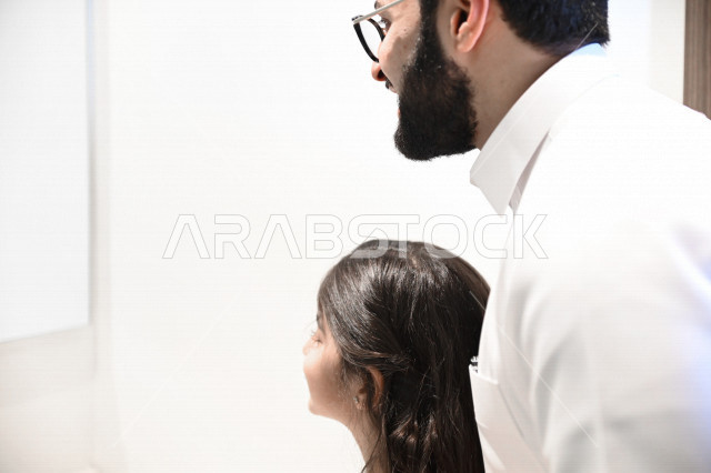 رجل عربي خليجي سعودي يساعد ابنته في تنظيف اسنانها والعناية بها ،تجنب تسوس الاسنان وامراض اللثة ، النظافة الشخصية والاهتمام بالنفس ، الرعاية الصحية للاطفال