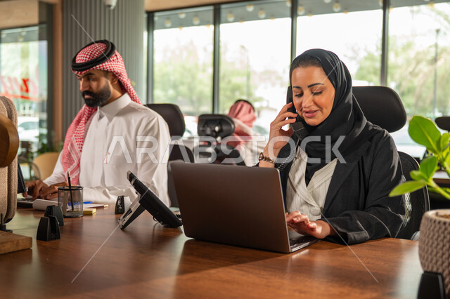 مفهوم الاستعلامات والاستفسارات، موظفة عربية خليجية سعودية محجبة مبتسمة تعمل في خدمة العملاء تقوم بالرد على الهاتف، الاجابه والرد على الأسئلة، العمل وادخال البيانات على الحاسوب، متابعة وتطوير العمل