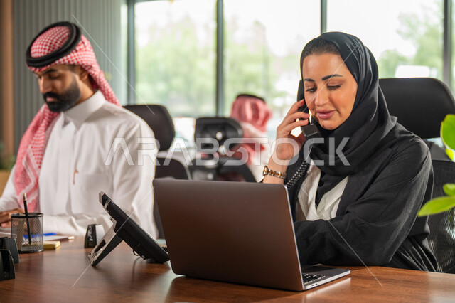 مفهوم الاستعلامات والاستفسارات، موظفة عربية خليجية سعودية محجبة مبتسمة تعمل في خدمة العملاء تقوم بالرد على الهاتف، الاجابه والرد على الأسئلة، العمل وادخال البيانات على الحاسوب، متابعة وتطوير العمل