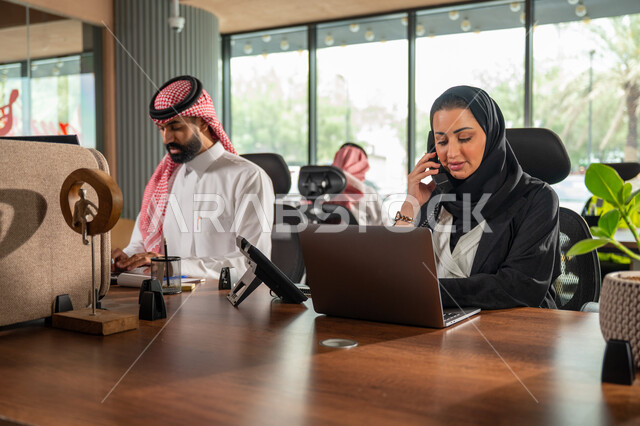 مفهوم الاستعلامات والاستفسارات، موظفة عربية خليجية سعودية محجبة مبتسمة تعمل في خدمة العملاء تقوم بالرد على الهاتف، الاجابه والرد على الأسئلة، العمل وادخال البيانات على الحاسوب، متابعة وتطوير العمل