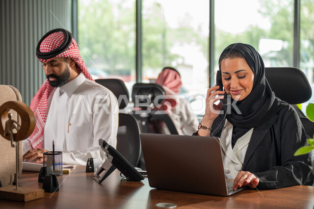 مفهوم الاستعلامات والاستفسارات، موظفة عربية خليجية سعودية محجبة مبتسمة تعمل في خدمة العملاء تقوم بالرد على الهاتف، الاجابه والرد على الأسئلة، العمل وادخال البيانات على الحاسوب، متابعة وتطوير العمل