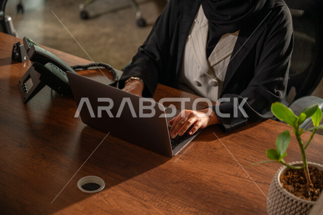 Data entry and typing via keyboard, integrating work with technology and technology, possessing the skill of fast typing on the keyboard, a close-up image of the hands of a Saudi Arabian Gulf woman wearing an abaya working on a laptop, administrative office job tasks