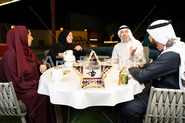 كرم الضيافة وحسن الاستقبال في شهر رمضان المبارك، تبادل الأحاديث بين أفراد الأسرة، أجواء عائلية دينية رمضانية سعيدة، ديكور وزينة المناسبات الإسلامية، عائلة عربية خليجية اماراتية مجتمعة في جلسة ليلية خارجية في احدى الشاليهات