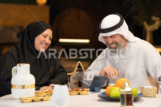 التواصل عبر الوسائل التقنية الحديثة، قضاء وقت ممتع في جلسة خارجية في احدى الشاليهات، زينة وديكور المناسبات والأعياد الاسلامية، أجواء عائلية سعيدة في شهر رمضان المبارك، زوجان عربيان خليجيان اماراتيان يقومان بإجراء مكالمة فيديو بإيماءات السعادة والسرور