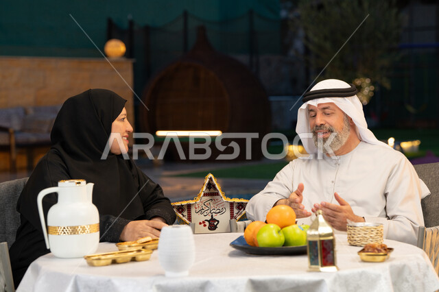 أجواء عائلية سعيدة في شهر رمضان المبارك، تبادل الأحاديث والتسامر بين الزوجين، أسرة عربية خليجية إماراتية تقضي أوقات ممتعة في جلسة خارجية في احدى الشاليهات، ديكورات وزينة المناسبات والأعياد الاسلامية