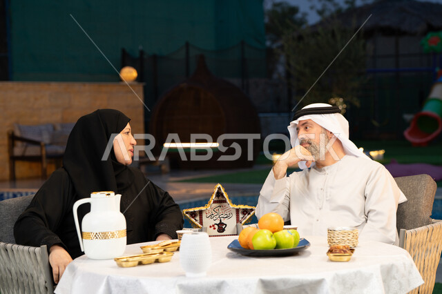 ديكورات وزينة المناسبات والأعياد الاسلامية، جلسة خارجية في احدى الشاليهات الراقية، أجواء عائلية سعيدة في شهر رمضان المبارك، تبادل الأحاديث والتسامر بين الزوجين، أسرة عربية خليجية إماراتية تقضي أوقات ممتعة في الهواء الطلق