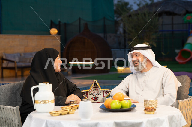 تبادل الأحاديث والتسامر بين الزوجين، أسرة عربية خليجية إماراتية تقضي أوقات ممتعة في جلسة خارجية في احدى الشاليهات، أجواء عائلية سعيدة في شهر رمضان المبارك، ديكورات وزينة المناسبات والأعياد الاسلامية