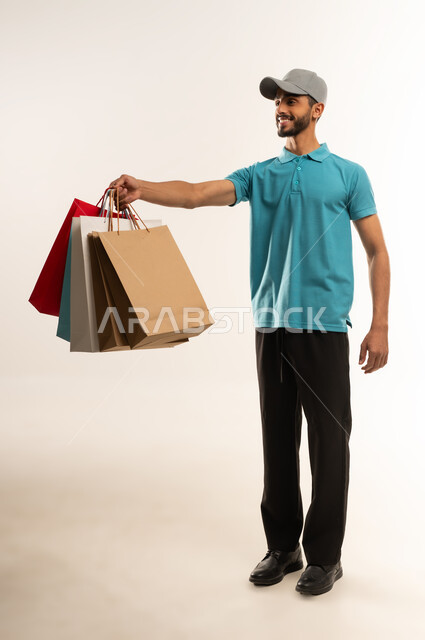 Online shopping and ordering, online delivery networks in the Gulf, integrating business with technology, portrait of a young Arab Gulf Omani man wearing casual clothes and a gray hat working as a sales representative, a Saudi man delivering orders, full body, white background