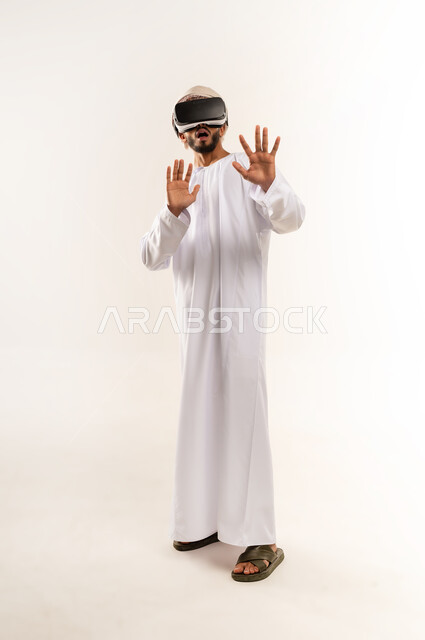 المتعة و التسلية بالمشاهدة عبر نظارة الواقع الافتراضي، التطور التقني والتكنولوجي, الاحساس بملامسة شئ ما، بورتريه لشاب عربي خليجي عماني يرتدي الدشداشه والكمه ينظر من خلال نظارات ثلاثية الأبعاد (الفي ار), الاندماج ومحاكاة العالم الخيالي والنظر الى الافلام الواقعيه، خلفيه بيضاء .