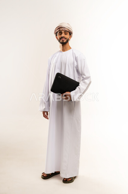 الشعور بالسرور لتحقيق أهداف الشركة, الذهاب إلى دوام العمل بنشاط, بورتريه لرجل عربي عماني خليجي مبتسم يرتدي الدشداشة والكمة ينظر إلى الكاميرا يحمل حقيبة يد سوداء , الاهتمام بالأناقة والمظهر الخارجي، صورة الجسم بالكامل, خلفية بيضاء .