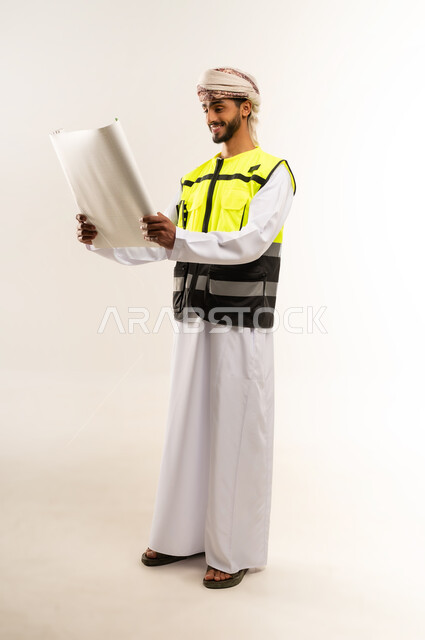 Professional project management, concept of engineering and architectural construction, looking with gestures of happiness and pleasure, working in the field of engineering, supervising engineering project plans, portrait of an Arab Gulf Omani engineer wearing a dishdasha, a keffiyeh and a protective vest holding a planner in his hands, professions and jobs for young people in the Sultanate of Oman, full body image, white background.