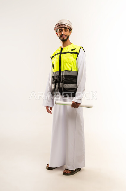 Working in the field of engineering, supervising engineering project plans, the concept of engineering and architectural construction, a portrait of an Arab Gulf Omani engineer wearing a dishdasha, a keffiyeh and a protective vest, holding a planner in his hands, professions and jobs for young people in the Sultanate of Oman, a full-length body image, a white background.
