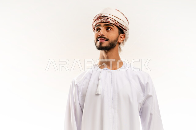تحديد موقع معين ، الاهتمام بالأناقة والمظهر الخارجي، مفهوم القوة والرجولة، بورتريه مقرب لرجل عربي خليجي عماني يرتدي الدشداشه والعمامة يقوم بالنظر الى مكان ما جانبا، ايماءات الثقة بالنفس، خلفية بيضاء .