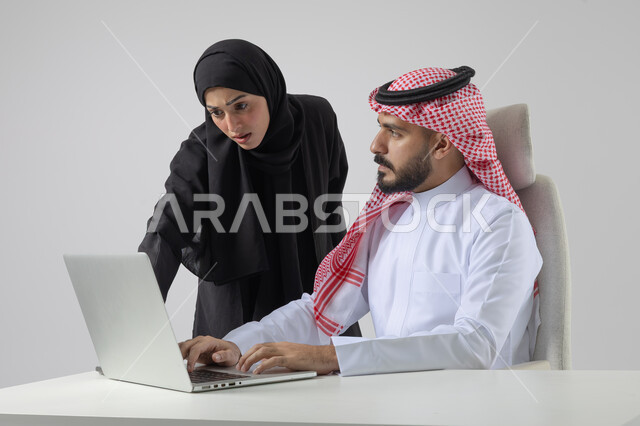 تبادل الاراء والخبرات، بورتريه لرجل وسيدة اعمال عربيان سعوديان خليجيان في مقر الشركة، ادارة العمل باستخدام الحاسب المحمول، الوحده والعمل الجماعي، تحقيق اهداف الشركة، مناقشة وتوزيع مهام العمل، تطوير العمل وحل المشكلات، مهن ووظائف سعودية مكتبية، خلفية بيضاء