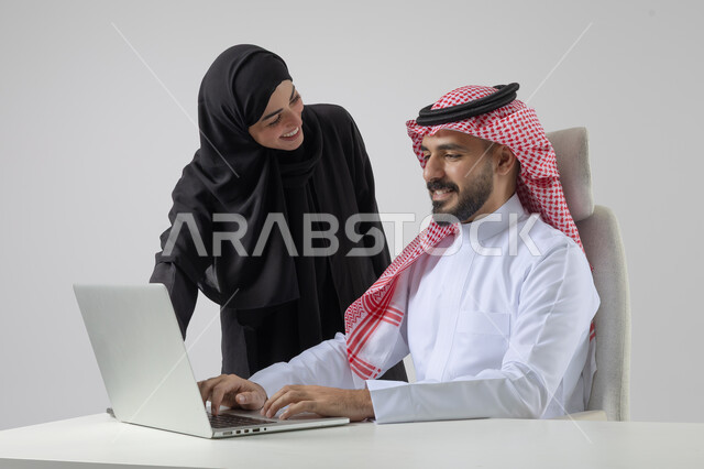  الوحده والعمل الجماعي، تبادل الاراء والخبرات، بورتريه لرجل وسيدة اعمال عربيان سعوديان خليجيان في مقر الشركة، ادارة العمل باستخدام الحاسب المحمول، تحقيق اهداف الشركة، مناقشة وتوزيع مهام العمل، تطوير العمل وحل المشكلات، مهن ووظائف سعودية مكتبية، خلفية بيضاء