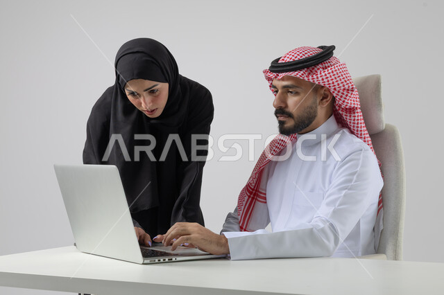  الوحده والعمل الجماعي، تبادل الاراء والخبرات، بورتريه لرجل وسيدة اعمال عربيان سعوديان خليجيان في مقر الشركة، ادارة العمل باستخدام الحاسب المحمول، تحقيق اهداف الشركة، مناقشة وتوزيع مهام العمل، تطوير العمل وحل المشكلات، مهن ووظائف سعودية مكتبية، خلفية بيضاء