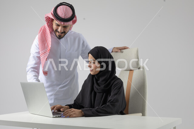  الوحده والعمل الجماعي، تبادل الاراء والخبرات، بورتريه لرجل وسيدة اعمال عربيان سعوديان خليجيان في مقر الشركة، ادارة العمل باستخدام الحاسب المحمول، تحقيق اهداف الشركة، مناقشة وتوزيع مهام العمل، تطوير العمل وحل المشكلات، مهن ووظائف سعودية مكتبية، خلفية بيضاء