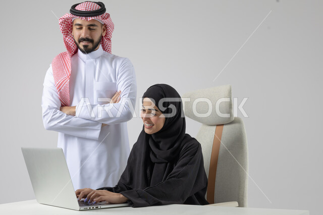  الوحده والعمل الجماعي، تبادل الاراء والخبرات، بورتريه لرجل وسيدة اعمال عربيان سعوديان خليجيان في مقر الشركة، ادارة العمل باستخدام الحاسب المحمول، تحقيق اهداف الشركة، مناقشة وتوزيع مهام العمل، تطوير العمل وحل المشكلات، مهن ووظائف سعودية مكتبية، خلفية بيضاء